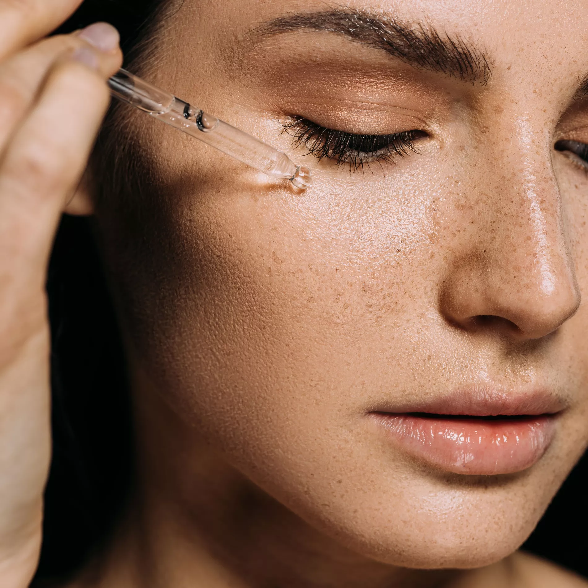 Close-up of glowing, hydrated skin with a serum dropper